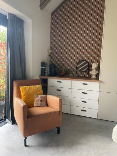 a living room with a chair and a dresser at Bed & breakfast De Loeghoeve in Anderen