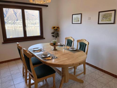 a dining room with a wooden table and chairs at Bella Fosano Casa in Gambarogno