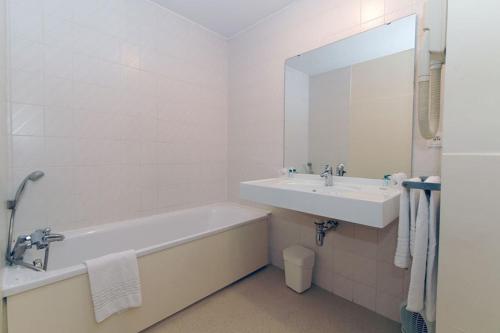 a bathroom with a tub and a sink and a mirror at Hôtel du Vigan in Albi