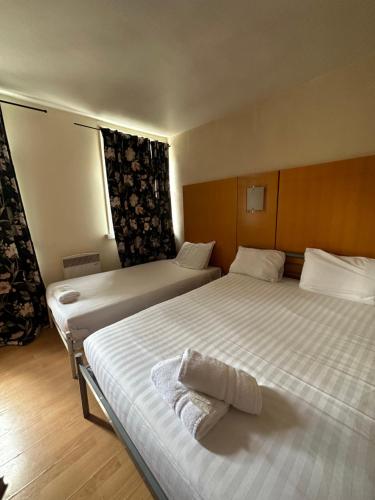 فندق بيركلي كورت في لندن: سريرين في غرفة الفندق مع سريرين مطلة على السرير
