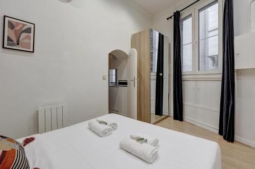 106 - Fabulous studio in Champs Elysees في باريس: غرفة نوم بسرير ابيض عليها مناشف