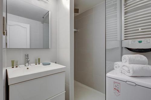 a white bathroom with a sink and a mirror at 106 - Fabulous studio in Champs Elysees in Paris