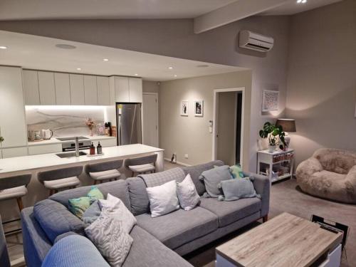 ein Wohnzimmer mit einem Sofa und einer Küche in der Unterkunft Modern Two-Bedroom Home in Merivale in Christchurch