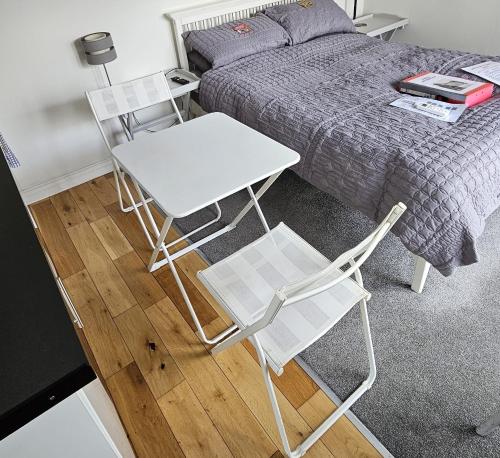 two white chairs and a table and a bed at Modern immaculate studio with aircon & parking in Bristol
