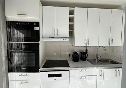 ニースにあるNice Rivieraの白いキャビネットと黒の電化製品が備わるキッチン