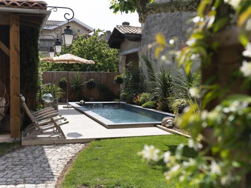 a pool in a yard with a chair and a fence at La Maison Mulatô, demeure privée d'hôtes, piscine & spa Libourne, Saint-Emilion in Libourne