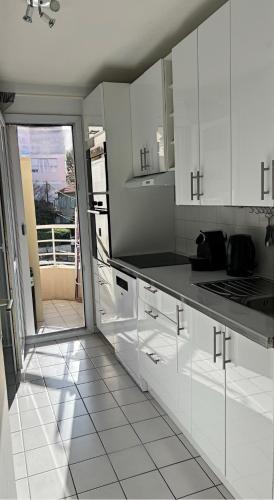 une cuisine avec des armoires blanches et des comptoirs noirs dans l'établissement Nice Riviera, à Nice