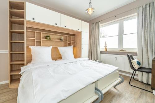1 dormitorio con 1 cama blanca grande y 1 silla en meine "Syltkoje", en Tinnum