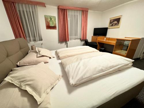 a hotel room with two beds and a desk at Hotel und Restaurant Pinkenburg in Wennigsen