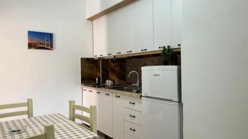 a kitchen with a white refrigerator and a table at Amel's Apartments Comfortable Family Stay Near Orikum Beach in Orikum