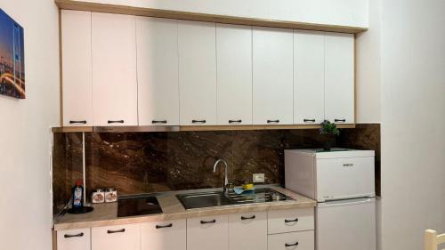 a kitchen with white cabinets and a sink and a refrigerator at Amel's Apartments Comfortable Family Stay Near Orikum Beach in Orikum