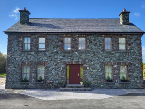 ein Steinhaus mit einer roten Tür und einer Bank in der Unterkunft Reeks Country House in Killarney