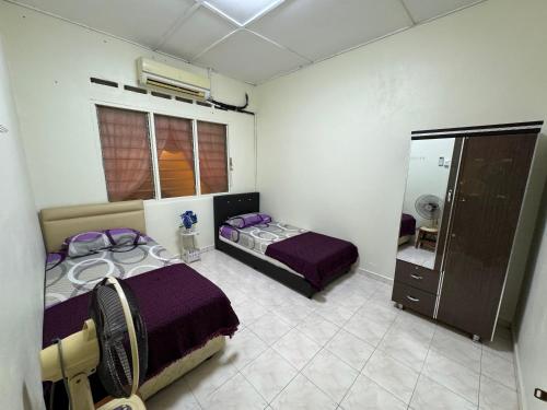 a bedroom with two beds and a mirror at Nur Rahmah Homestay Banting in Banting