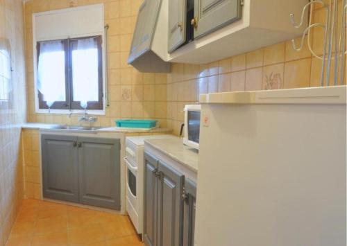 a kitchen with gray cabinets and a white refrigerator at RNET - MTA Apartaments A2 in Roses