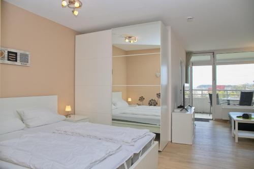 a white bedroom with a bed and a mirror at Kaiserhof App 786 inkl WLAN in Grömitz