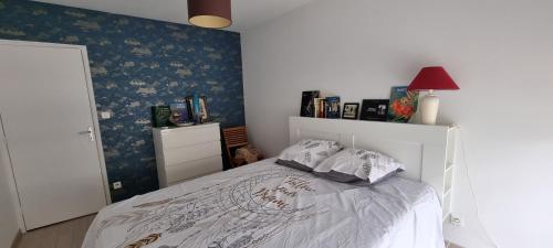 - une chambre avec un lit blanc et un mur bleu dans l'établissement SPITIMOU BORDEAUX, à Cenon