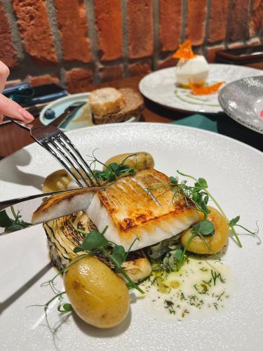 a plate of food with fish and potatoes on a table at Royal Tulip Warsaw Centre in Warsaw