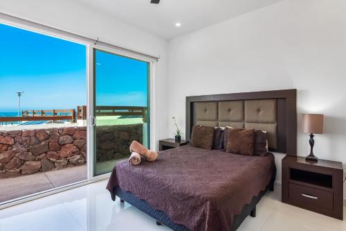 a bedroom with a large bed and a large window at Casa Marfil 26 - Playa Arcangel in Rosarito