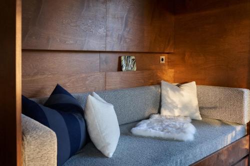 a couch with pillows on it in a room at Landet, Designer Cabins in the Swedish Archipelago in Västerljung