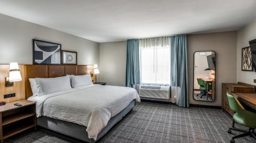 a hotel room with a bed and a desk and a window at Staybridge Suites Dallas Market Ctr Love Field by IHG in Dallas