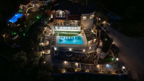 an aerial view of a house with a swimming pool at night at Geroulios Kastro, a Grand Estate, By ThinkVilla in Vatoudhiáris
