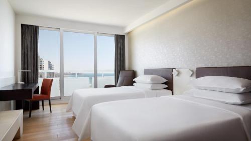 テルアビブにあるSheraton Grand Tel Avivのベッド2台とデスクが備わるホテルルームです。