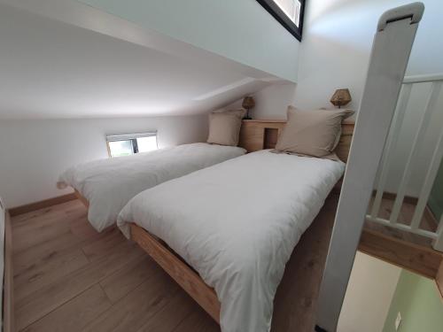 2 Betten in einem Zimmer mit weißen Wänden und Holzböden in der Unterkunft Le Pigeonnier in Flaujac-Poujols