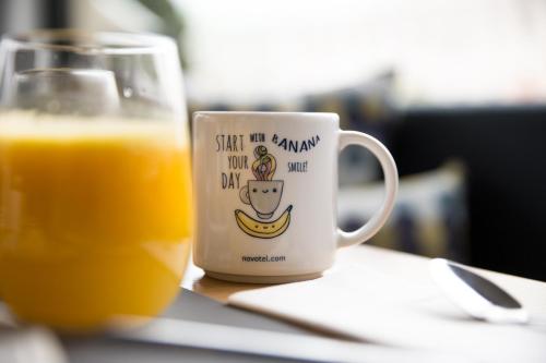 a cup of orange juice next to a glass of orange juice at Novotel Vilnius Centre in Vilnius