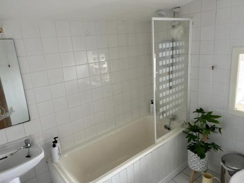 La salle de bains blanche est pourvue d'une baignoire et d'un lavabo. dans l'établissement Glenbeigh Holiday Cottage - Tigin Mamo, à Glenbeigh