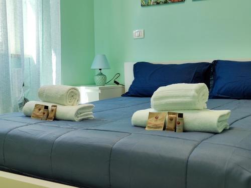 - un lit bleu avec des serviettes et des oreillers dans l'établissement Gioiello nel Borgo Marinaro, à Civitanova Marche