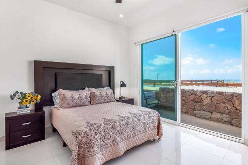 een slaapkamer met een bed en een groot raam bij Casa Fresno 23 - Playa Arcangel in Rosarito