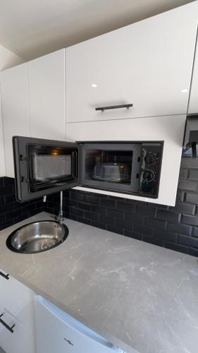 - une cuisine avec un four micro-ondes au-dessus d'un évier dans l'établissement Welcome to the black and White, à Villepinte