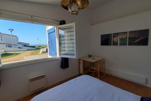 a bedroom with a bed and a window and a table at Villa Familiale, Vue sur Mer, Accès Direct Plage in Saint-Gilles-Croix-de-Vie