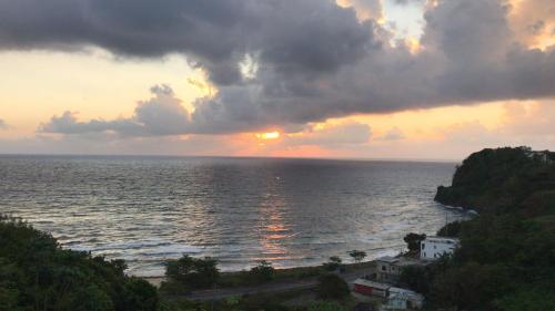 a sunset over the ocean with the sun setting at I VIEW - in Long Bay in Port Antonio