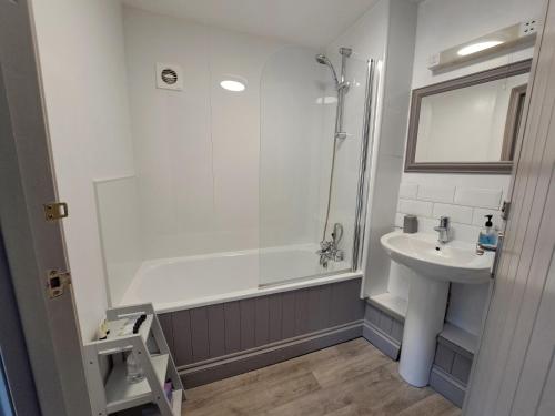 La salle de bains blanche est pourvue d'un lavabo et d'une douche. dans l'établissement The White Hart, à Oxford