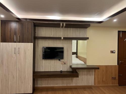 a room with a tv and a wall with a mirror at Pine Tree Resort in Nagarkot