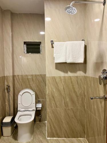a bathroom with a toilet and a shower with towels at Pine Tree Resort in Nagarkot