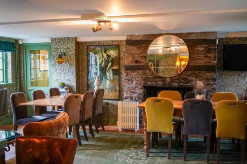 a dining room with a table and chairs and a fireplace at The Bluebell Country Inn, Crickhowell in Crickhowell
