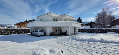 una casa blanca con una furgoneta estacionada en la nieve en Villa Juwel, en Altenmarkt im Pongau