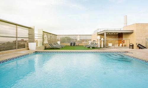 a large blue swimming pool on top of a building at Ilunion Barcelona in Barcelona