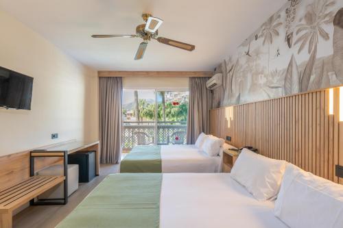 トレモリノスにあるHotel Parasol by Dorobeのベッド2台とテレビが備わるホテルルームです。