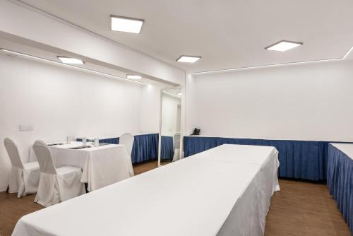 a room with a table and chairs and a white bed at Eurostars Gran Hotel Lugo in Lugo