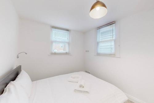 a white room with a bed and two windows at 1 Bed House with Garden sleeps 4 - 10 min to Station in London