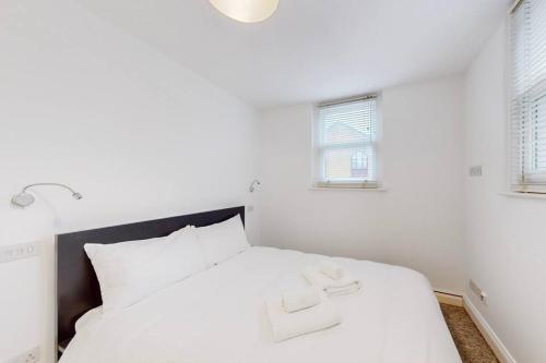 a white bed in a room with two windows at 1 Bed House with Garden sleeps 4 - 10 min to Station in London