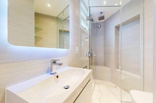 a white bathroom with a sink and a shower at 1 Bed House with Garden sleeps 4 - 10 min to Station in London