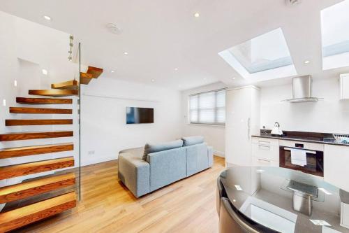a living room with a blue couch and a kitchen at 1 Bed House with Garden sleeps 4 - 10 min to Station in London