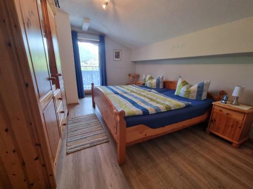 een slaapkamer met een bed met een blauw dekbed en een raam bij Bei Schneider's in Ruhpolding