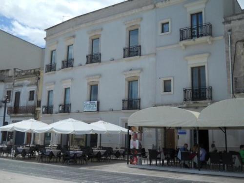 a building with tables and white umbrellas in front of it at Regina del Porto in Brindisi