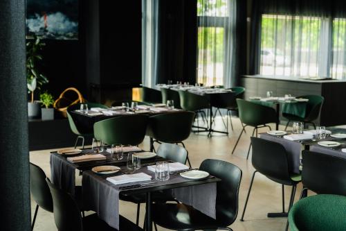a dining room with tables and green chairs at OTTO Hotel & Sun in Pāvilosta