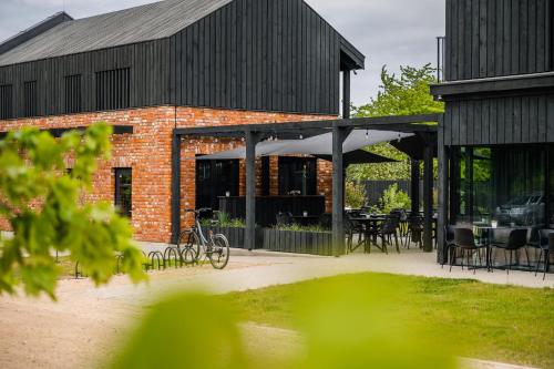 a brick building with a patio with tables and chairs at OTTO Hotel & Sun in Pāvilosta